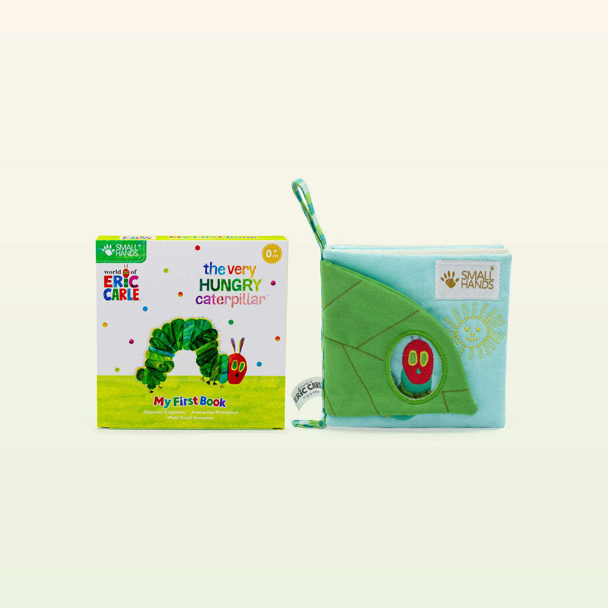 Small Hands Die Raupe Nimmersatt Montessori Fühlbuch – Verpackung und Stoffbuch mit grünem Blatt auf sanftem Creme-Hintergrund – ab 0 Monaten