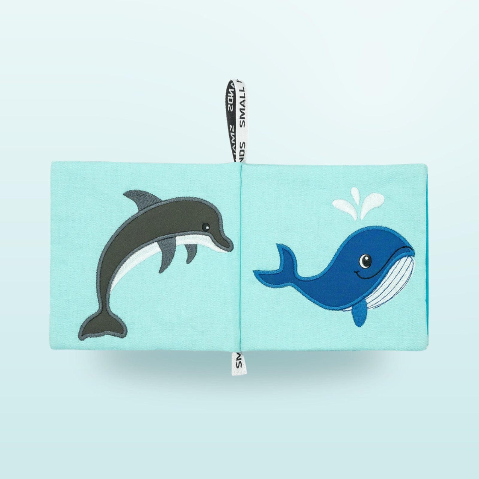 Small Hands Meeresbewohner Montessori Stoffbuch Doppelseite mit Delfin und Wal auf sanftem Unterwasser-Blau-Hintergrund – ab 1 Jahr